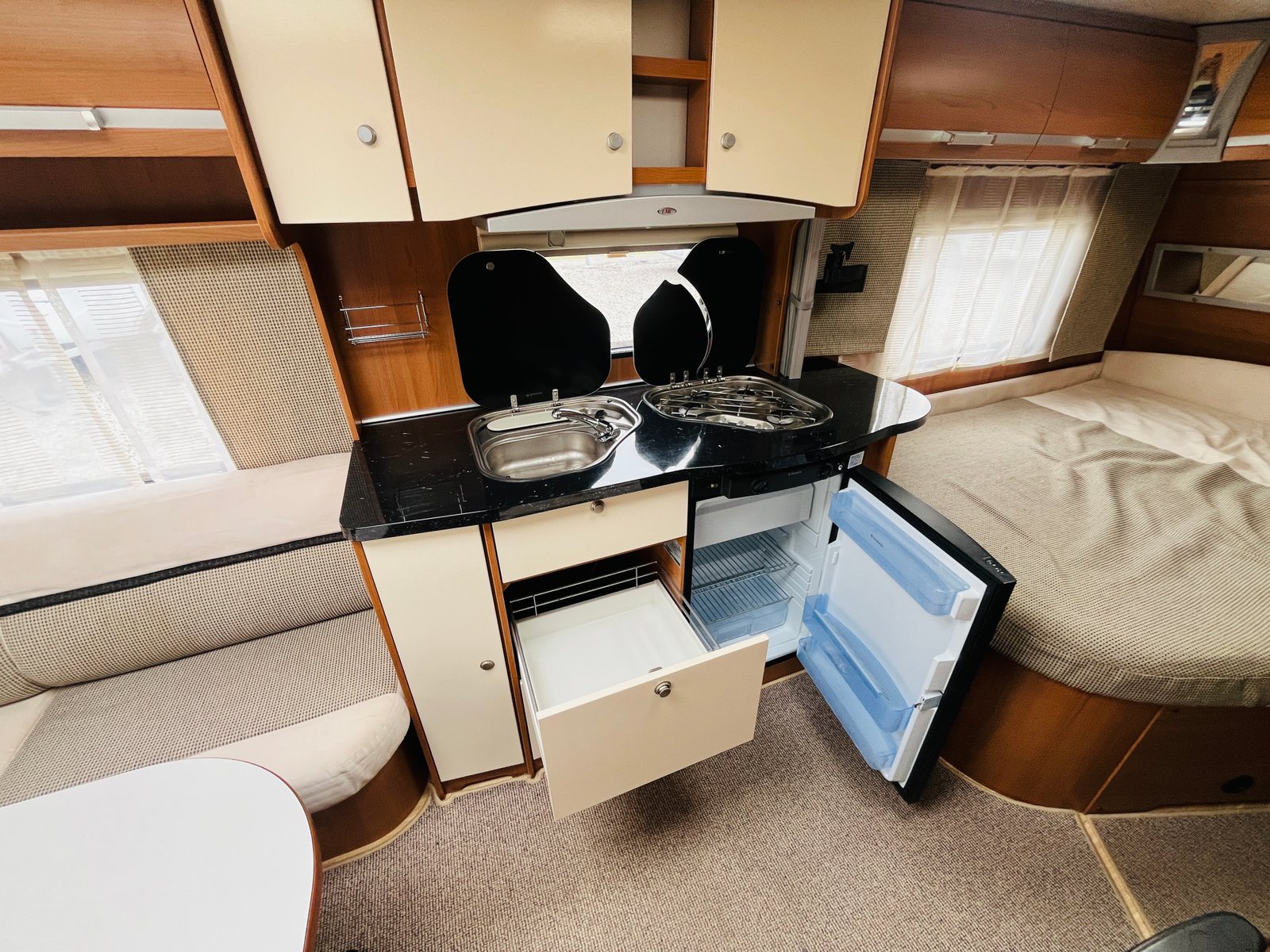 Obrázek interiéru karavanu s kuchyňským koutem a pohodlným sezením. Ideální pro cestování a odpočinek.