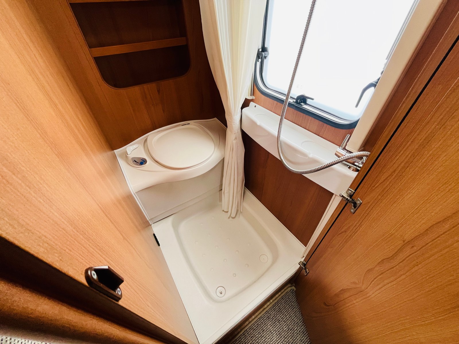 Obrázek interiéru karavanu s koupelnou, sprchou a toaletou v dřevěném designu. Komfort při kempování.