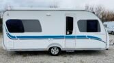 Karavan Adria 512 UP s moderním designem a bílou karoserií ve stylu s modrými detaily.