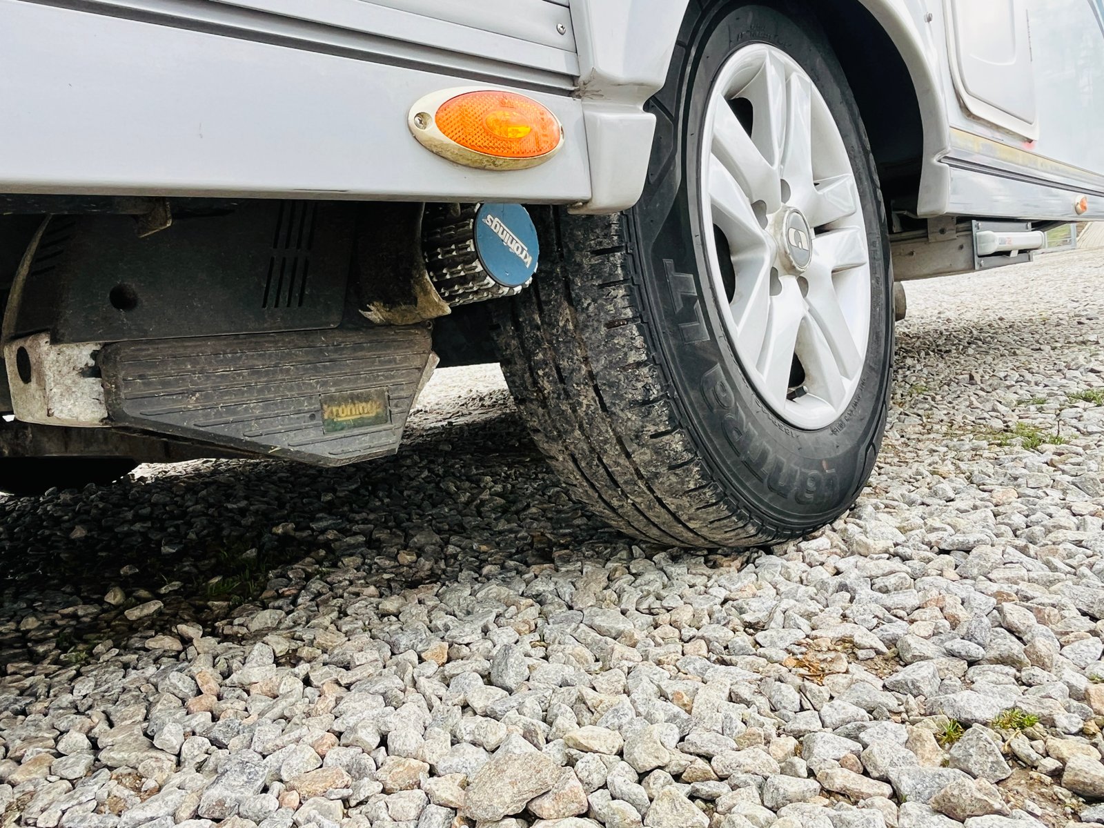 Obrázek zobrazuje obytné auto s pryžovými koly a podvozkem na kamenné cestě.