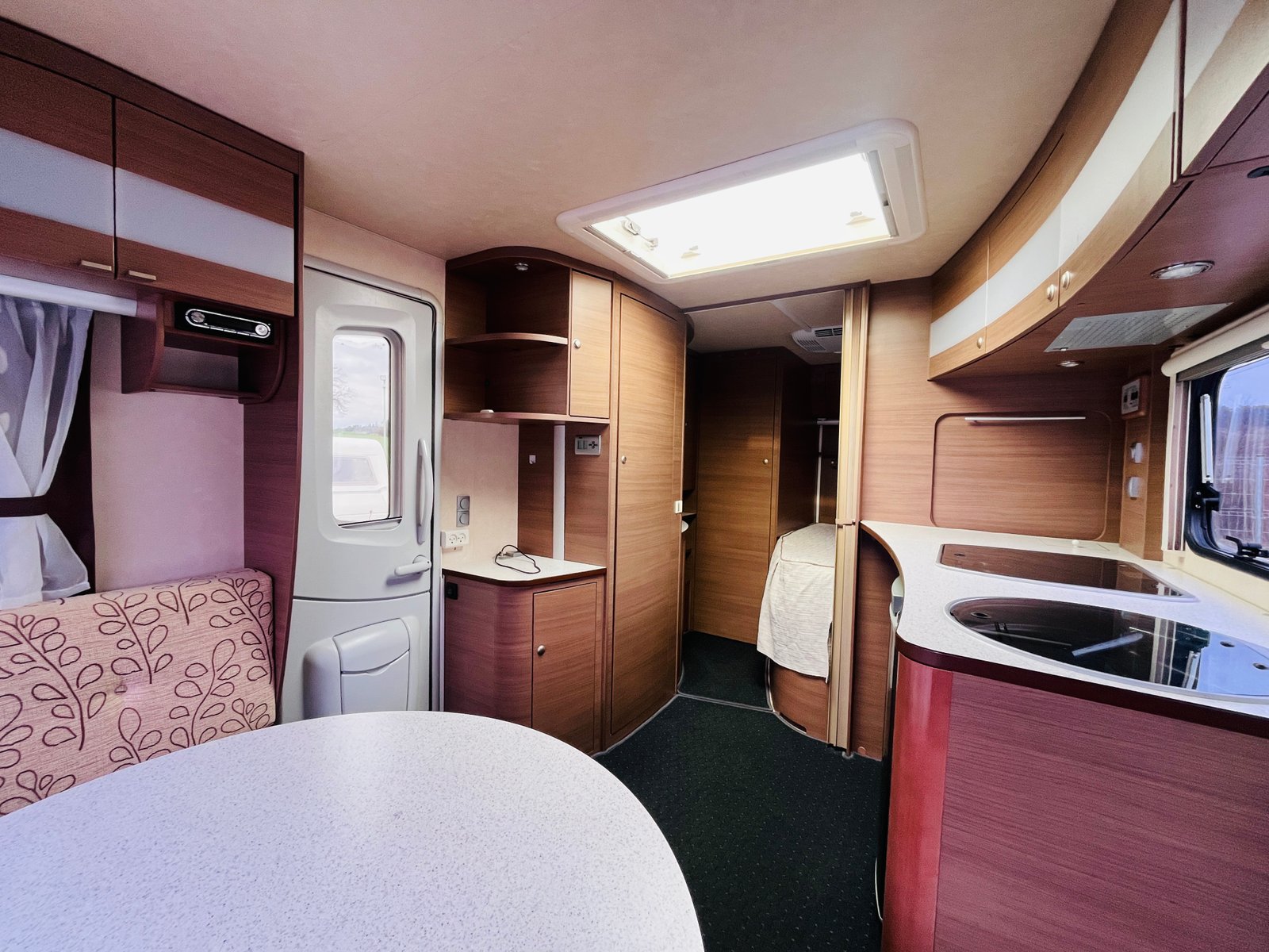 Interiér karavanu s moderním vybavením, dřevěné povrchy a pohodlné sezení. Ideální pro cestování a relaxaci.