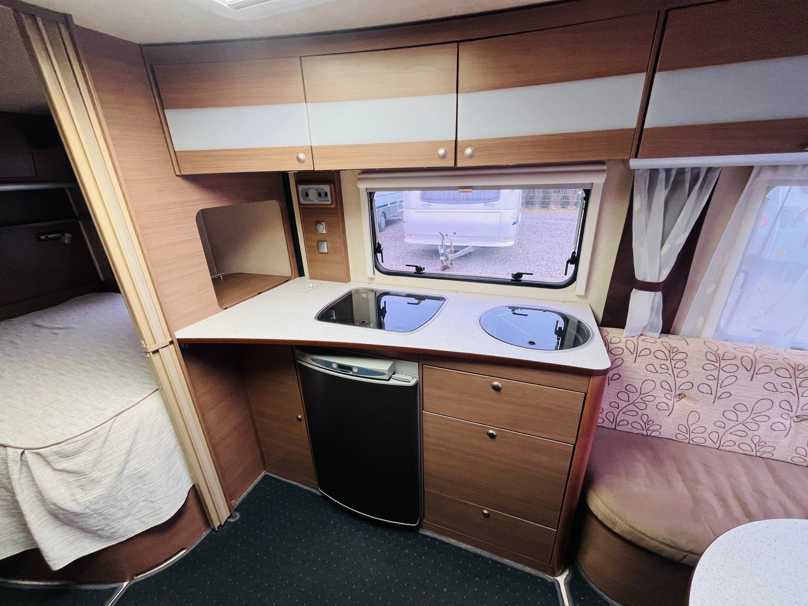 Interiér karavanu s kuchyňským koutem, skříněmi a pohodlným sezením. Ideální pro cestování a odpočinek.