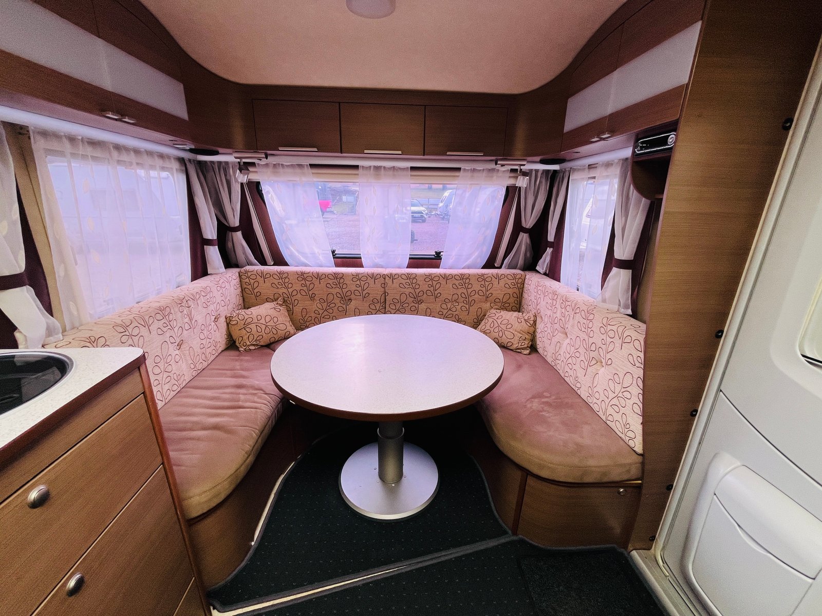 Interiér karavanu s pohodlným sezením a obývacím prostorem. Ideální pro kempování a cestování.
