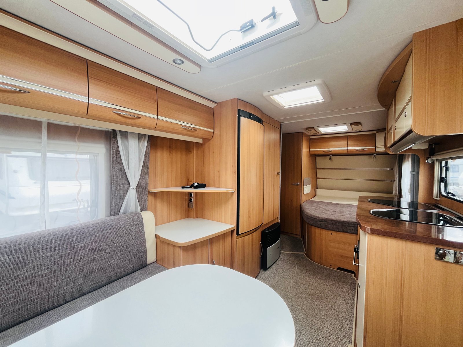 Obrázek interiéru karavanu s dřevěnými prvky a komfortním uspořádáním. Ideální pro dovolenou.