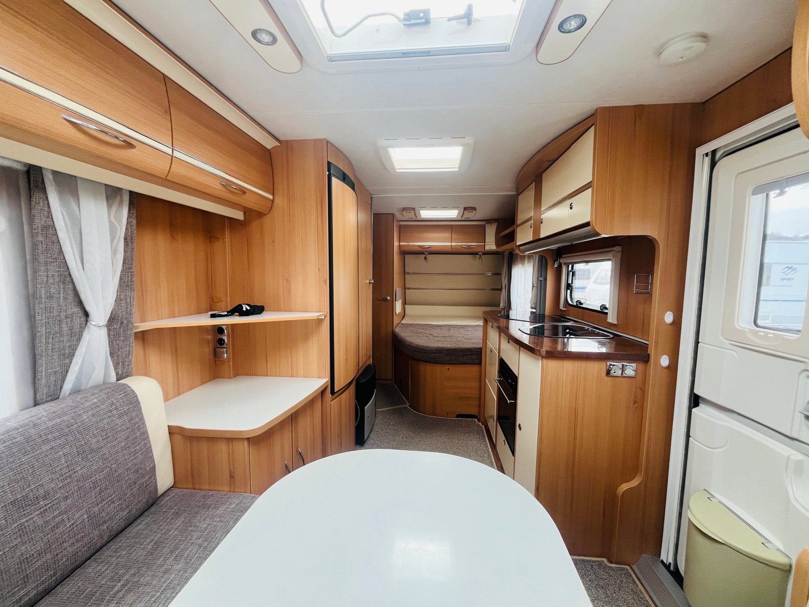 Interiér obytného auta, moderní dřevěný design, kuchyň a společenská část. Ideální pro pohodlné cestování.