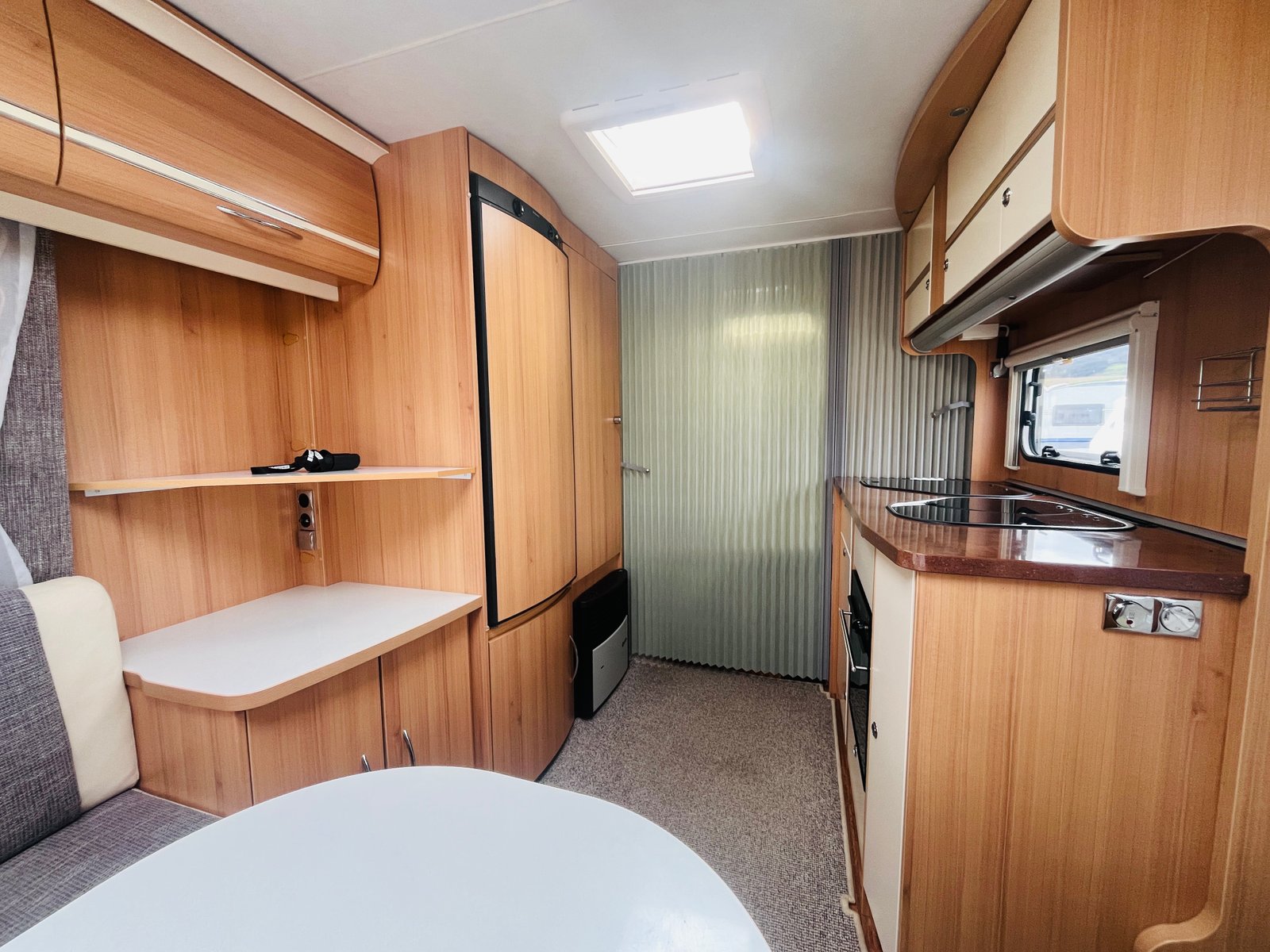 Interiér karavanu s moderním vybavením a dřevěnými akcenty. Ideální pro pohodlné kempování.