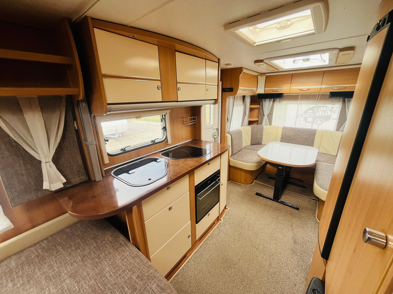 Moderní karavan s útulným interiérem, kuchyňkou a prostorným posezením. Ideální pro pohodlné cestování.
