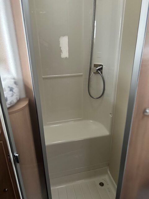 Obrázek interiéru obytného vozu s praktickou sprchou. Ideální pro pohodlné cestování!