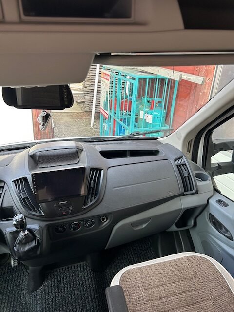 Interiér obytného auta s moderním ovládáním a prostornou kabinou. Ideální pro vaše dobrodružství na cestách!