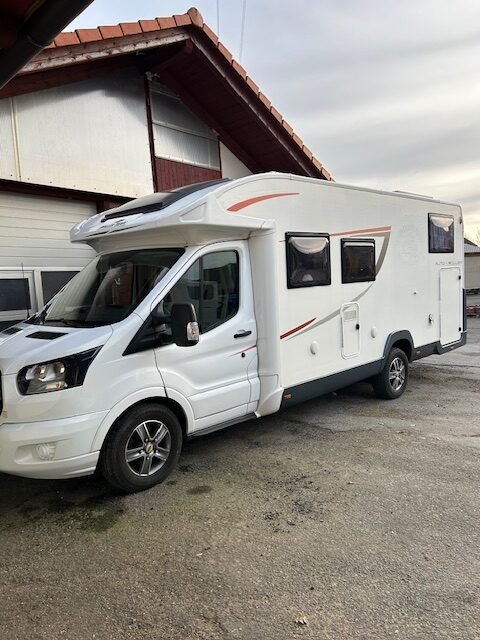 Obytné auto, bílé s černými detaily, zaparkované na rovné ploše. Ideální pro dobrodružství na cestách.