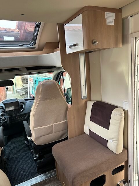 Interiér obytného auta s pohodlným sedadlem a praktickými úložnými prostory.