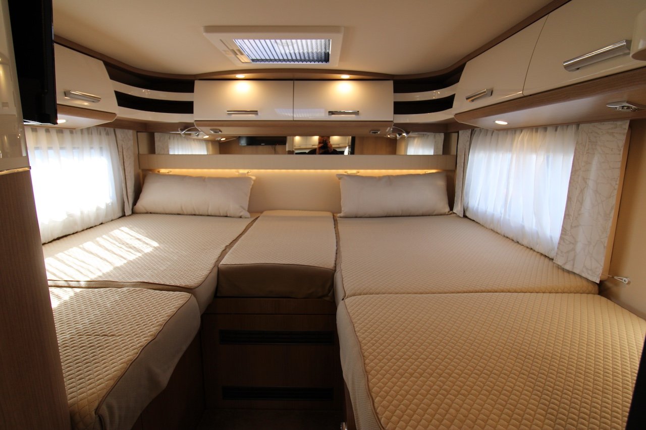 Obrázek zobrazuje prostorný interiér obytného auta s pohodlnými lůžky a příjemným osvětlením.