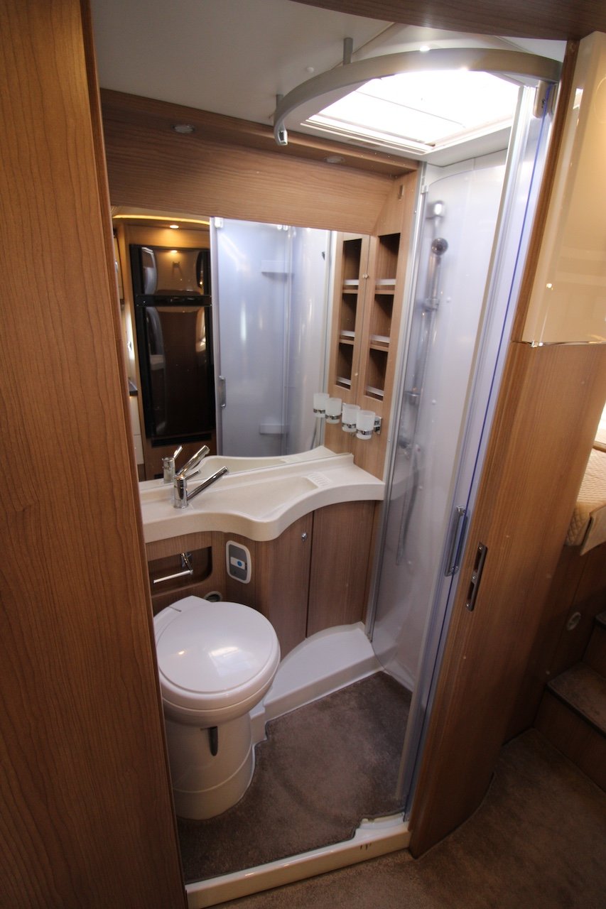 Obrázek interiéru s moderní koupelnou v obytném voze. Kvalitní design a funkčnost pro komfortní cestování.