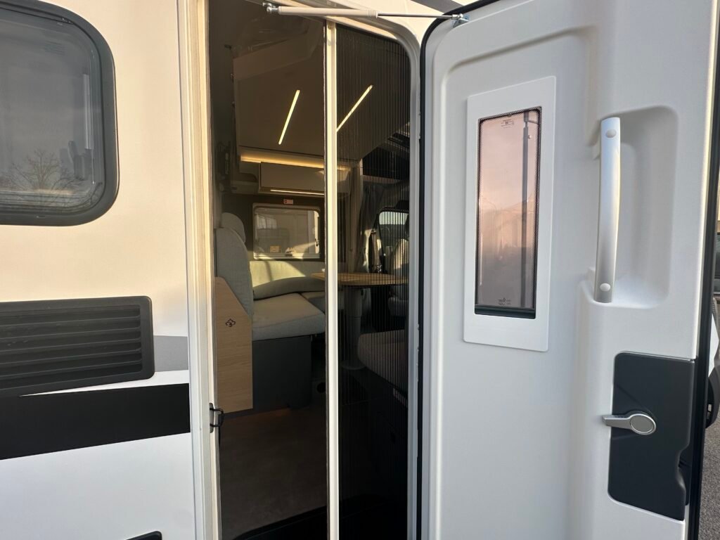 Obrázek zobrazuje vstup do obytného auta, moderního a prostorného interiéru.