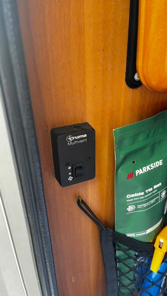 Na obrázku je ovládací panel Truma Multivent v interiéru obytného vozu. Ideální pro pohodlné užívání.