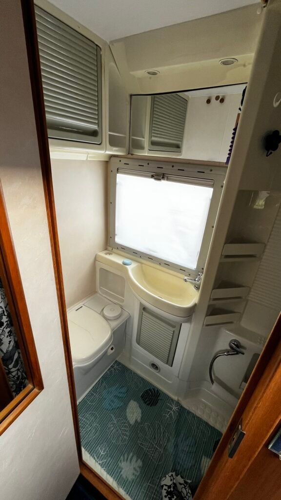 Koupelna v obytném voze s moderním vybavením. Umyvadlo, toaleta a sprchový kout. Komfort na cestách.