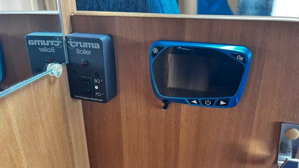 Obrázek z interiéru obytného vozu s ovládáním boileru Truma a displejem. Ideální pro pohodlné cestování.