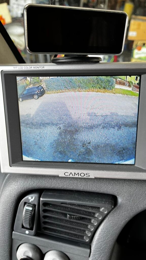 Obrázek z monitoru ukazuje parkování obytného auta. Značka a model nejsou viditelné.