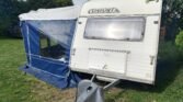 Karavan Confort s modrou plachtou, ideální pro kempování a dobrodružství v přírodě.