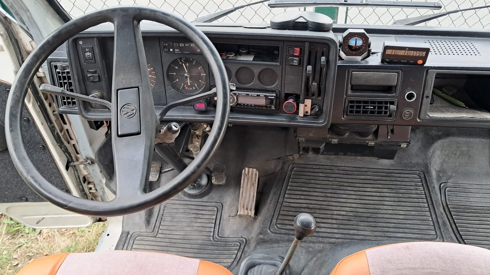 Interiér obytného auta Volkswagen s klasickým volantem a rádiem, připravený na dobrodružství.