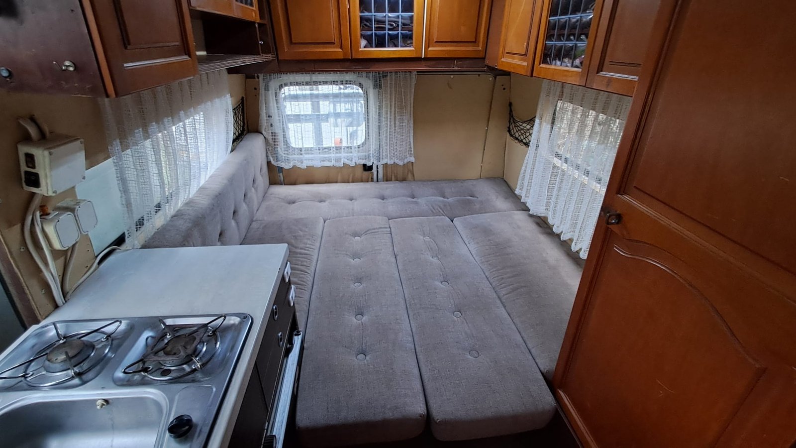 Obrázek interiéru karavanu s pohodlným posezením a kuchyňským koutem. Ideální pro dobrodružství na cestách.