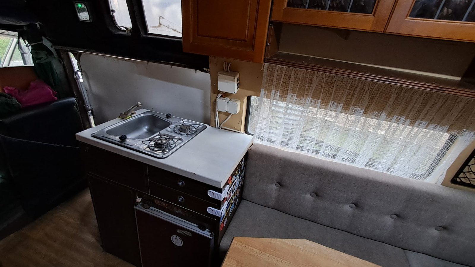 Interiér obytného vozu s kuchyňským koutem a pohodlným sezením. Ideální pro cestování a kempování.