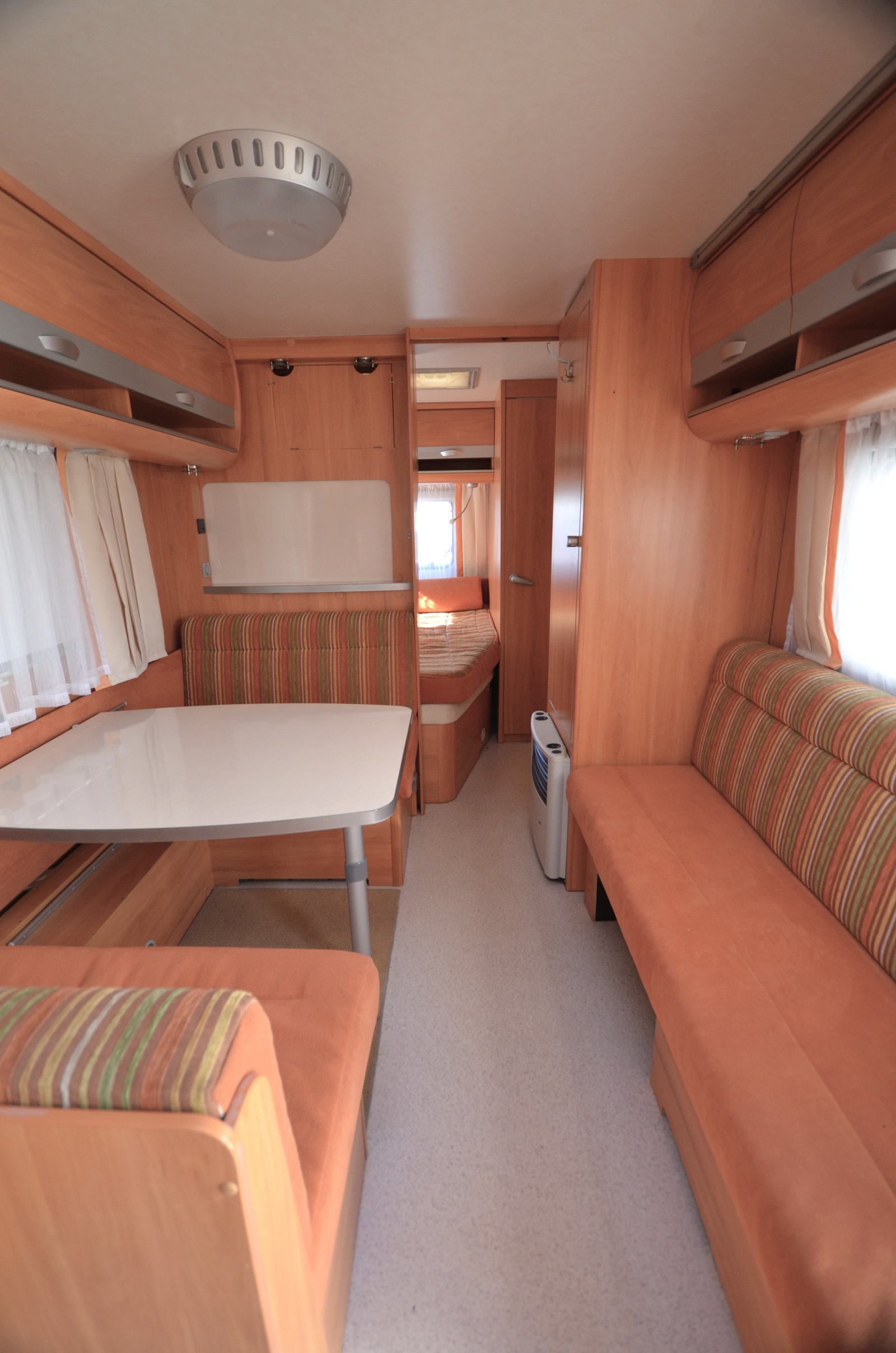 Pohodlný interiér karavanu s prostorným obývacím prostorem a pohodlnými sedacími soupravami. Ideální pro dovolenou.