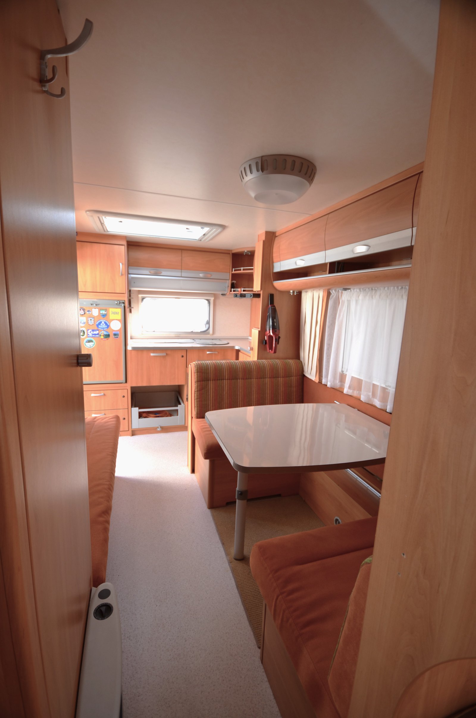 Interiér karavanu s příjemným sezením a kuchyní, ideální pro pohodové cestování a kempování.
