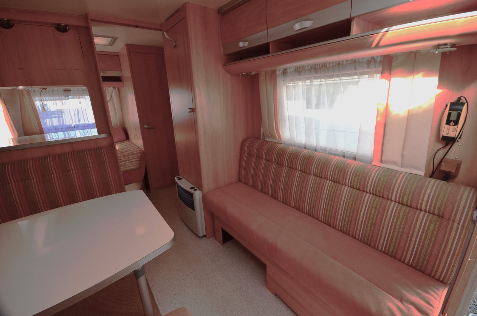 Útulný interiér karavanu s pohodlnými sedacími prvky a stolem. Ideální pro dovolenou na cestách.