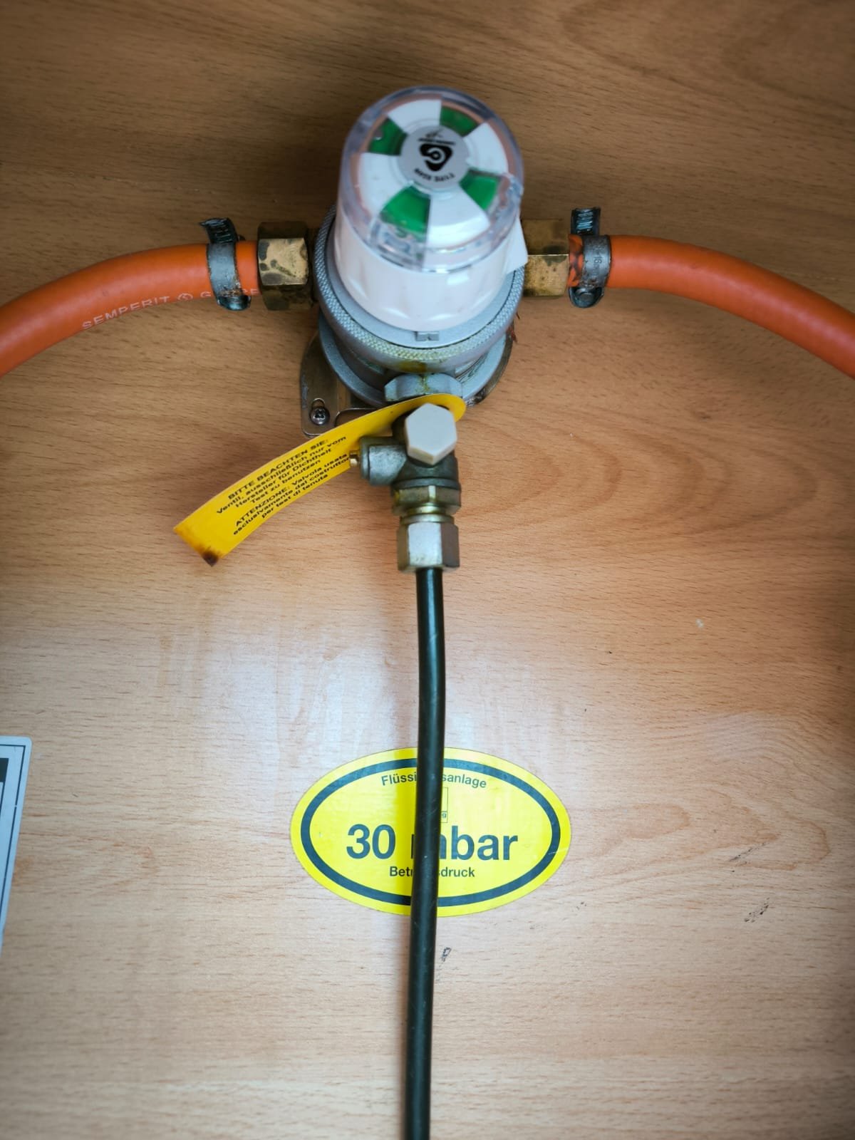 Obrázek ukazuje regulační ventil s hadicemi a značkou pro tlak na 30 mbar. Značka a model vozu nejsou viditelné.