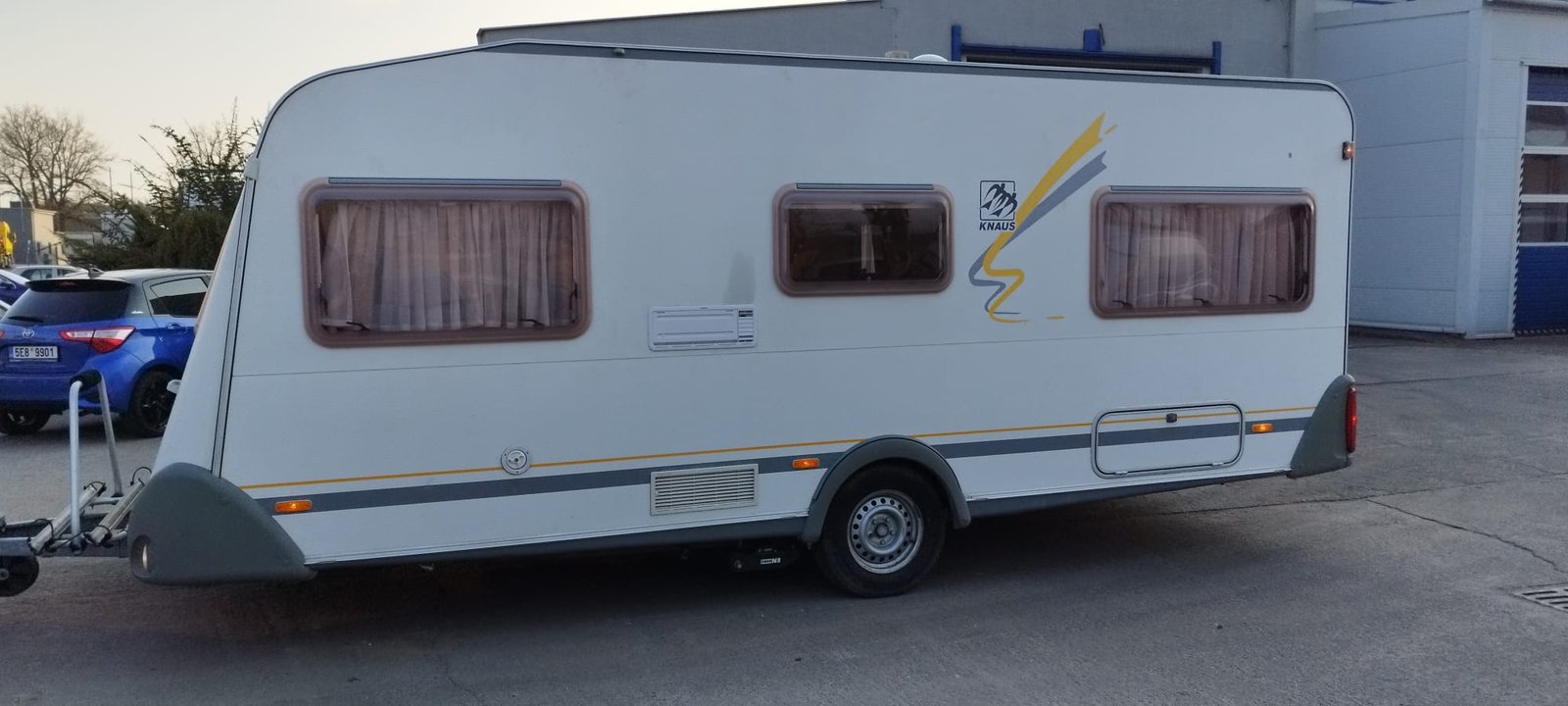 Karavan Knaus v bílém provedení s dekorativními prvky, ideální pro pohodlné cestování.