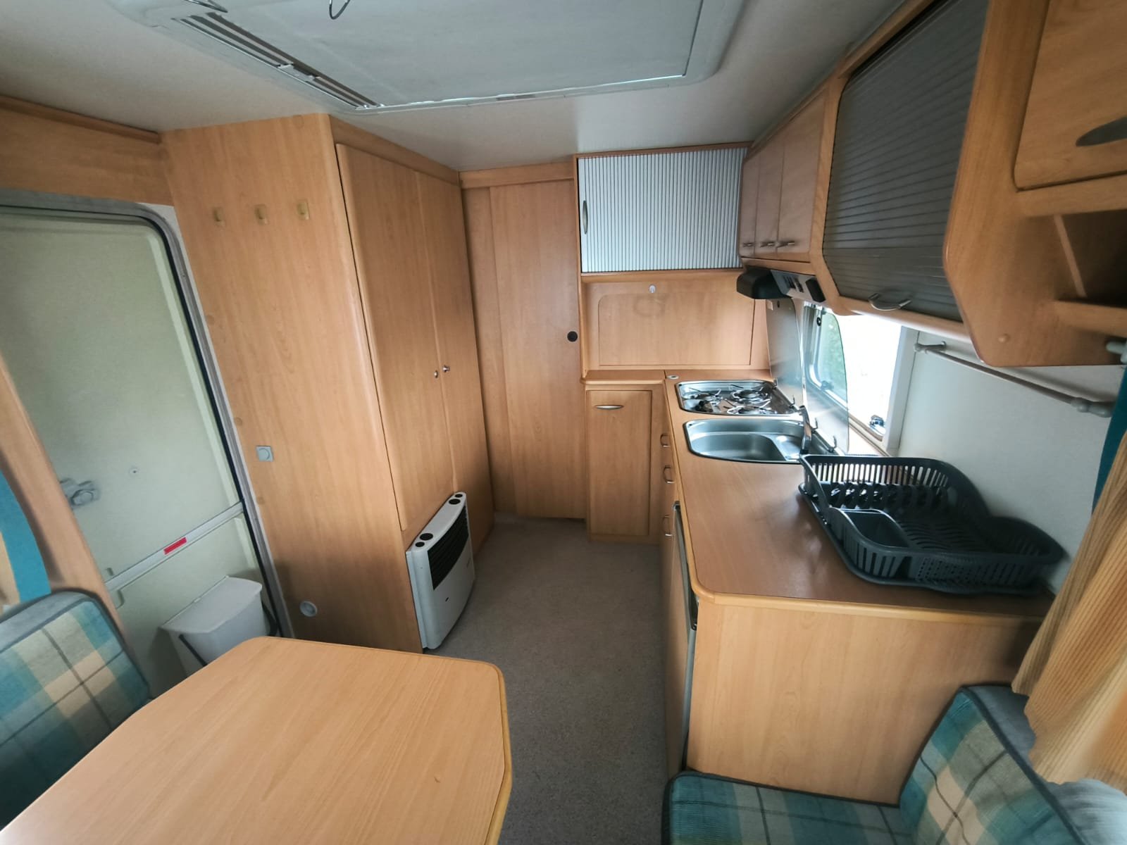 Interiér karavanu s dřevěnými skříněmi a vybavením pro vaření. Ideální pro cestování a kempování.