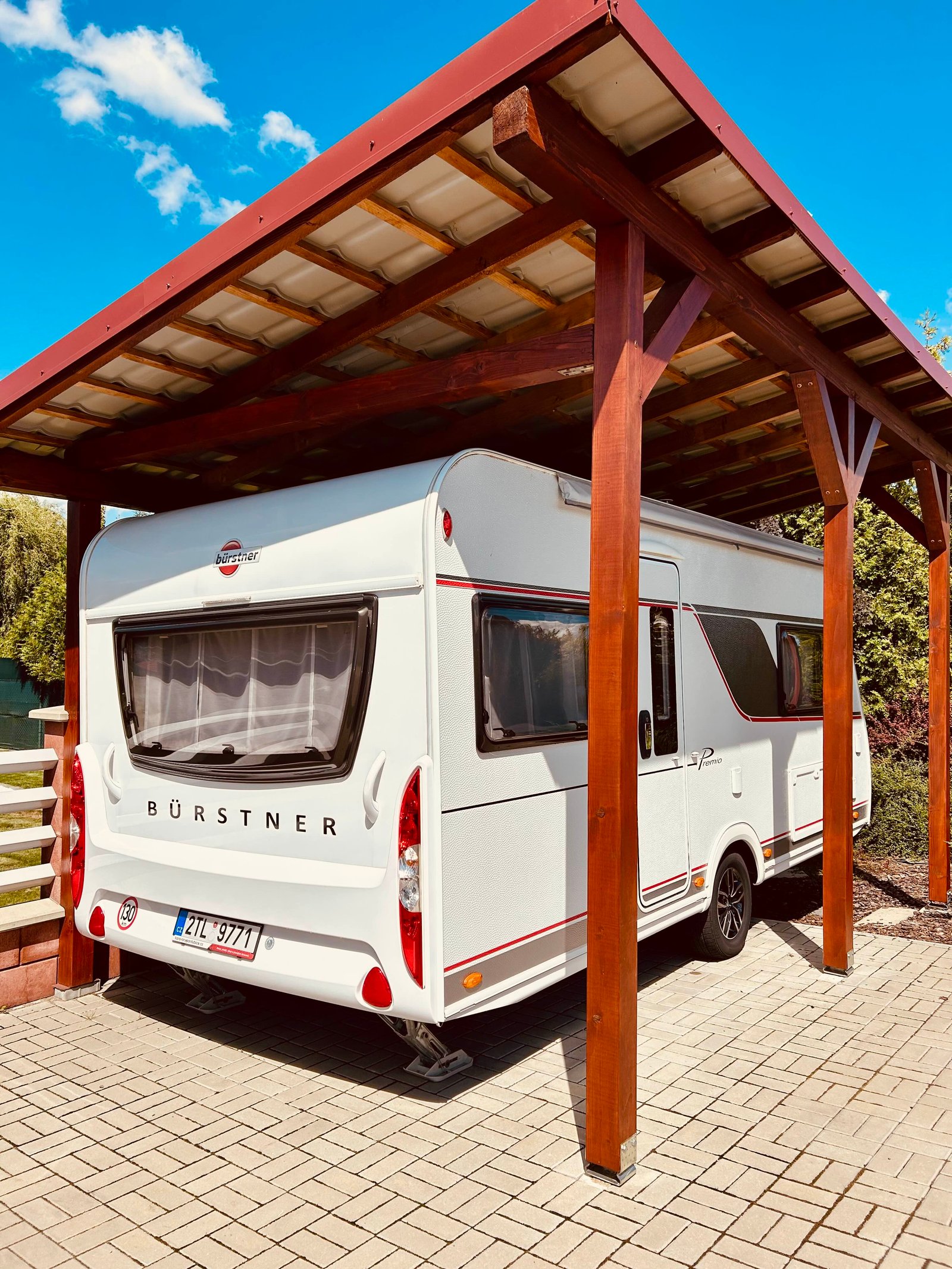 Karavan Bürstner pod přístřeškem, připravený na cesty s pohodlným zázemím.