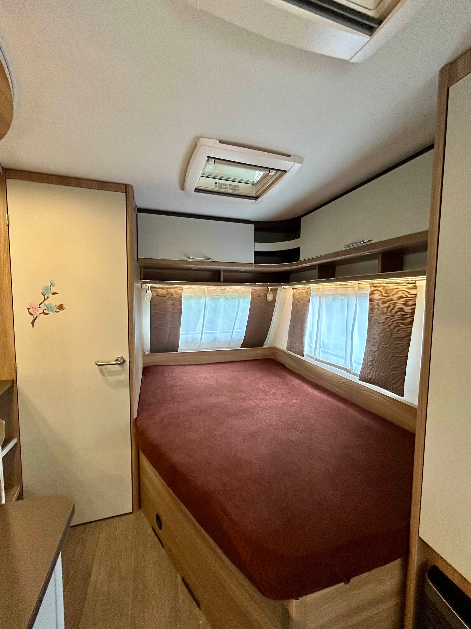 Interiér karavanu s pohodlnou postelí a elegantním dřevěným designem. Ideální pro rodinné dobrodružství.