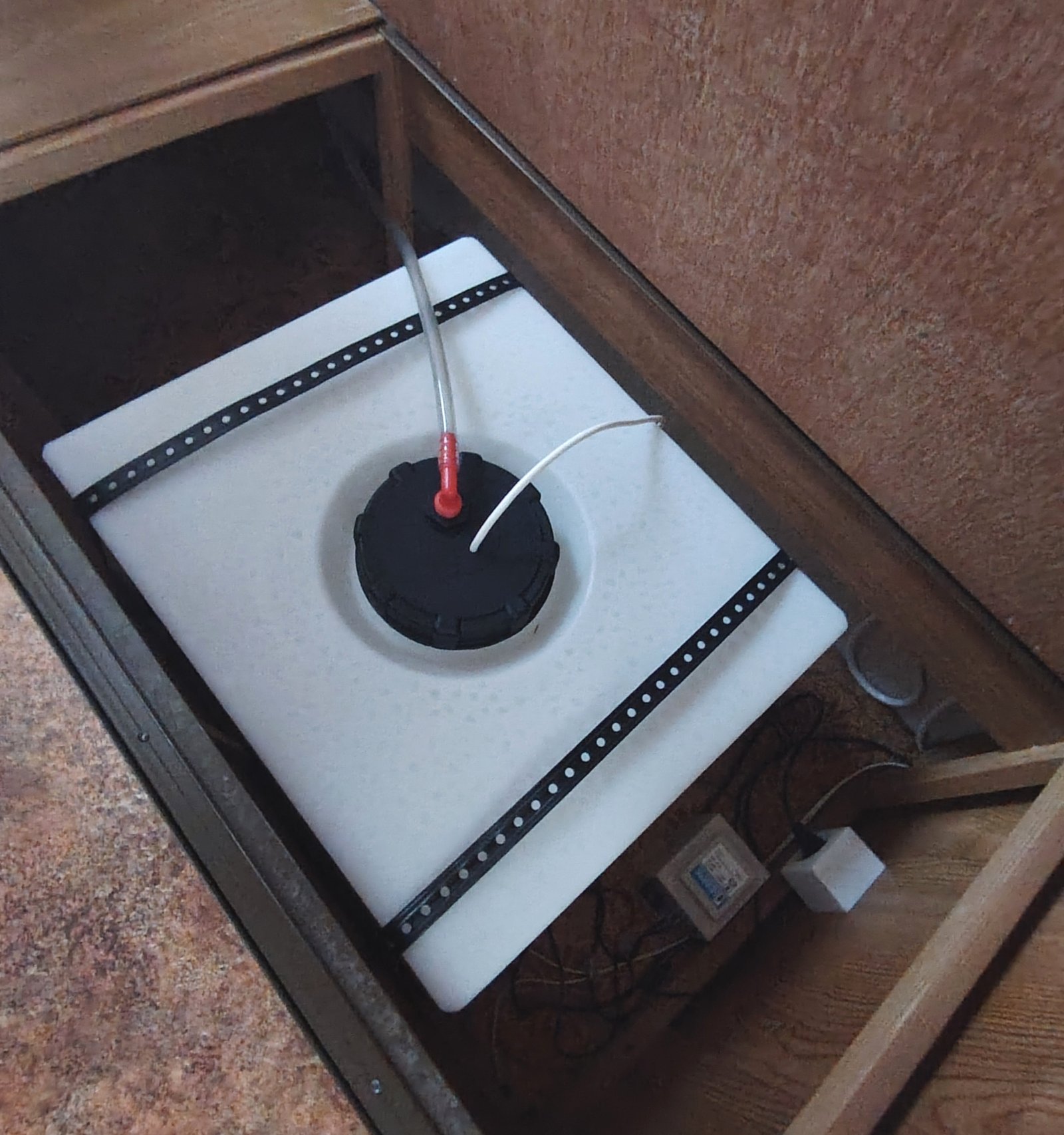 Obrázek znázorňuje nádrž s vývodem v interiéru obytného auta, ale značku a model není možné identifikovat.