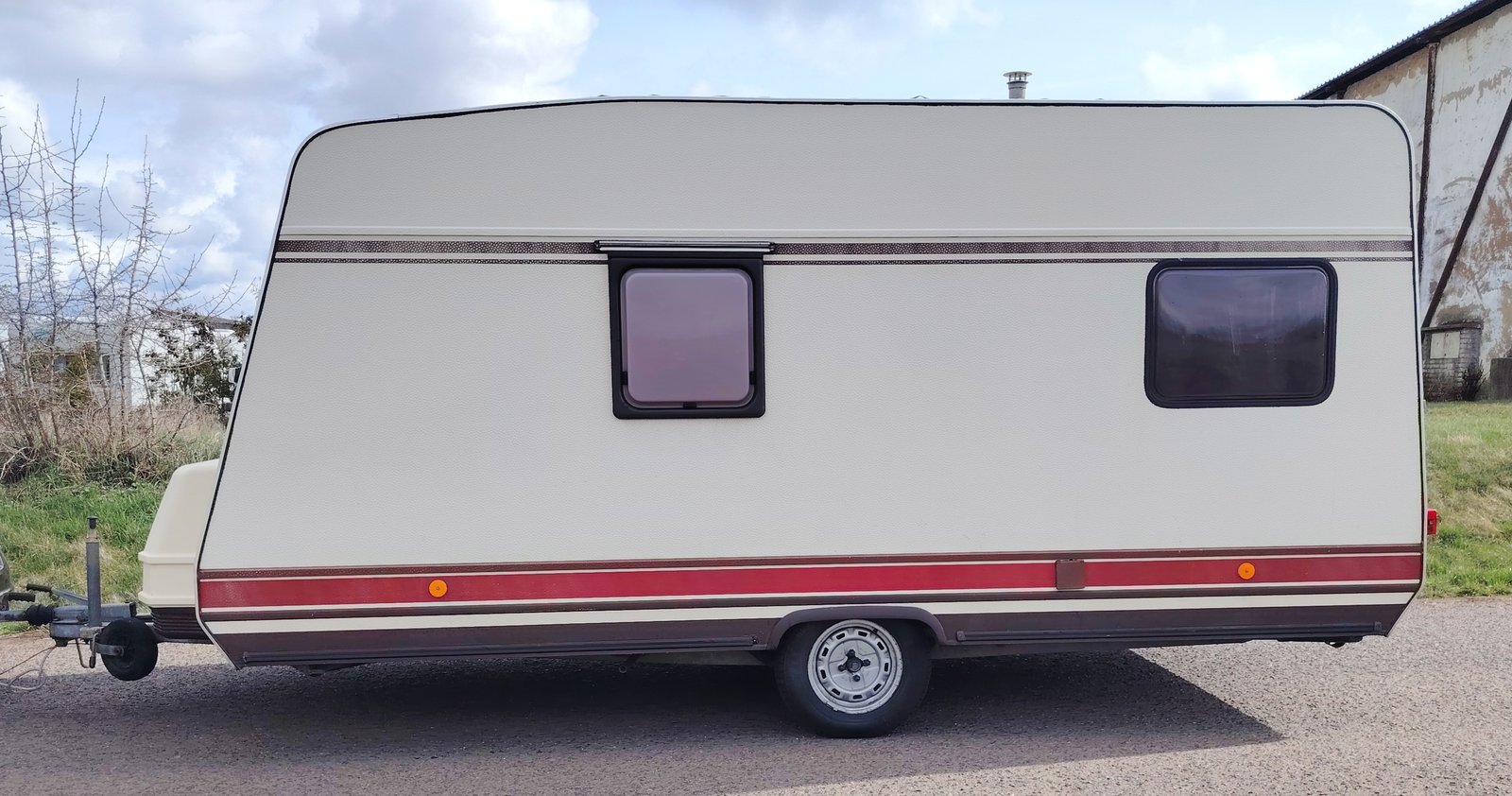 Karavan s bílým a červeným designem, ideální pro pohodlné cestování na výlety.