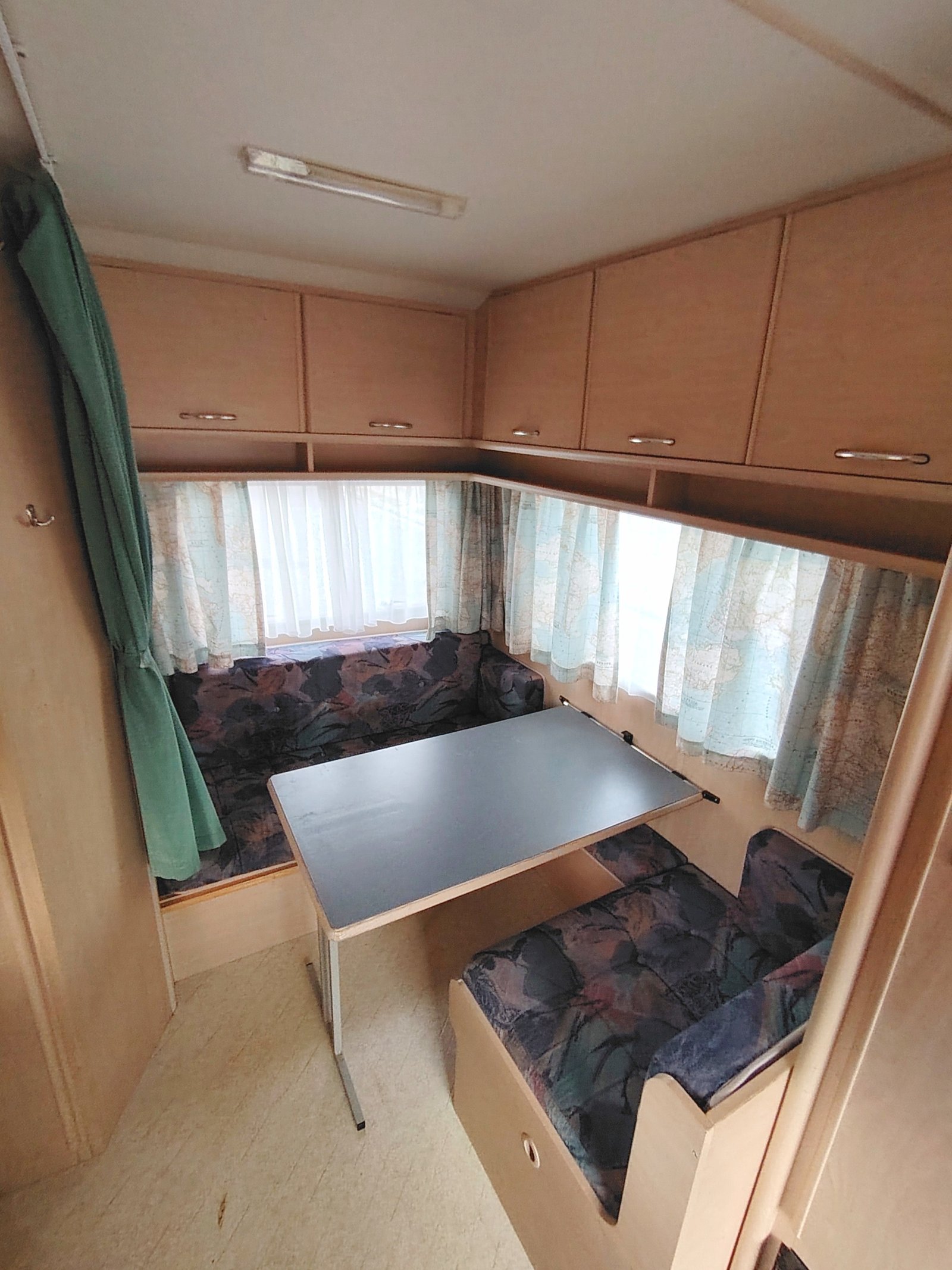 Interiér karavanu s obytnou zónou a stolem. Ideální pro pohodlné cestování a odpočinek.