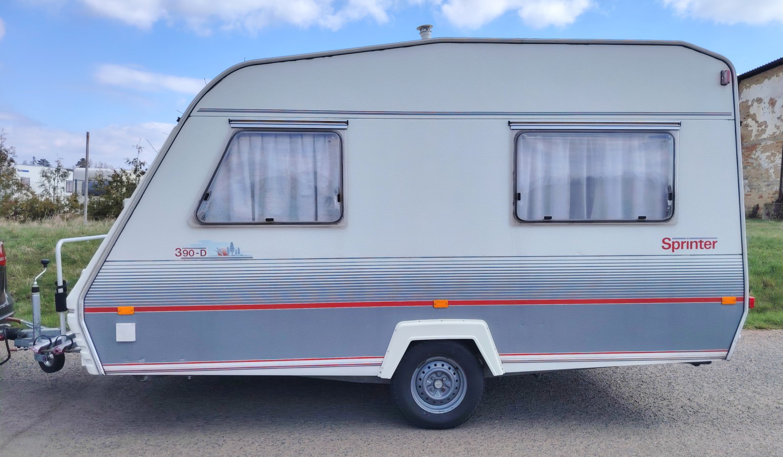 Karavan Sprinter 390-D, stylový s bílým a šedým potahem, ideální pro dobrodružství na cestách.