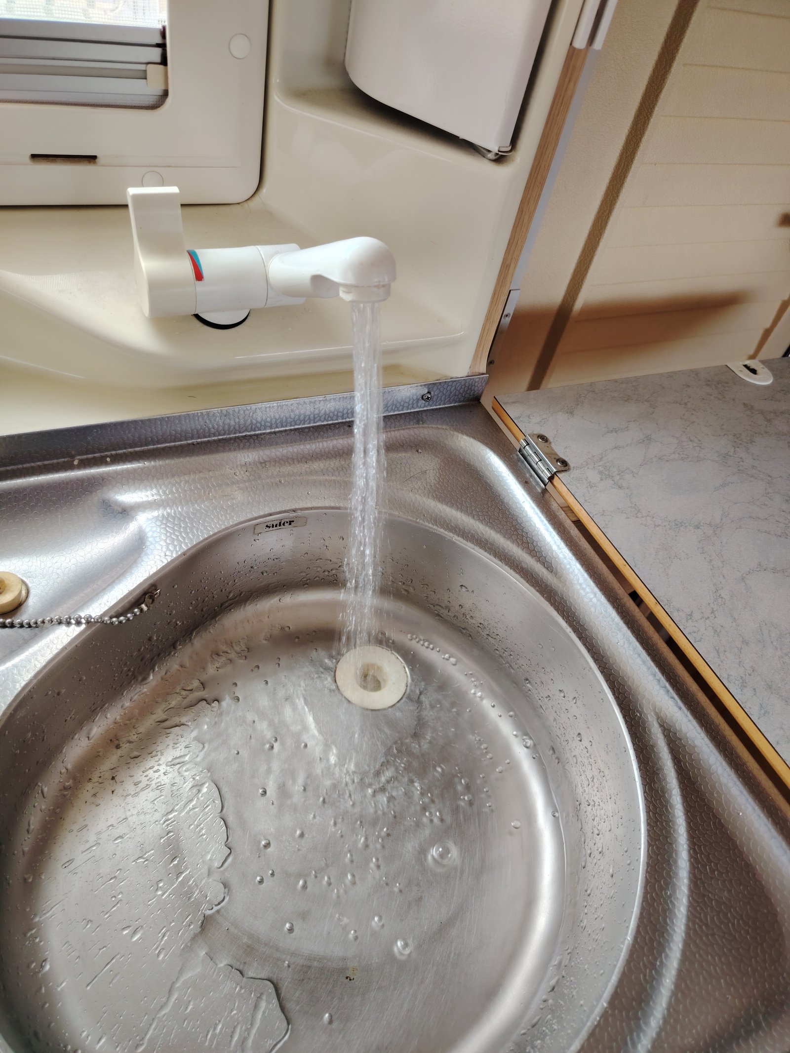 Obrázek ukazuje dřez s tekoucí vodou, pravděpodobně v karavanu. Snadný přístup k vodě při cestování.