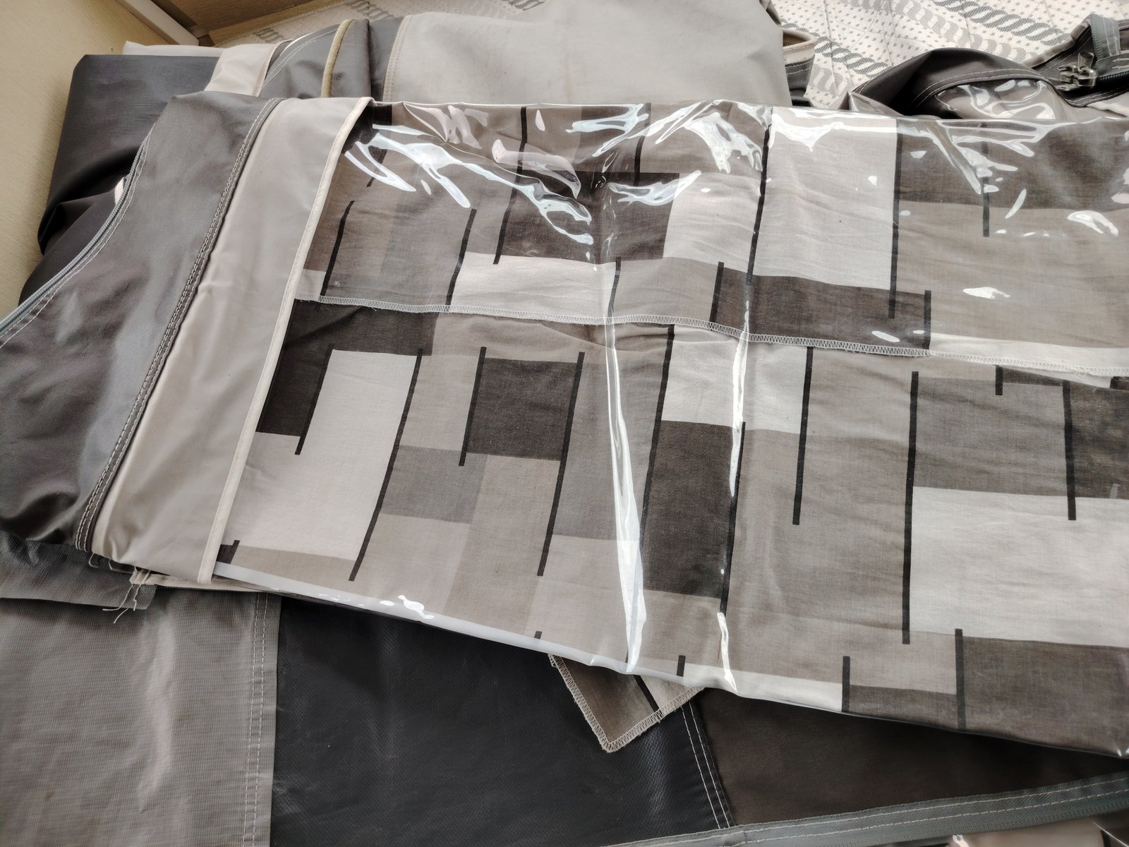 Na obrázku jsou látky v odstínech šedé a bílé, vhodné pro vybavení obytného vozu nebo karavanu.