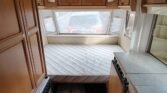 Prostorný interiér karavanu s dvojlůžkem a kuchyňským koutem. Ideální pro pohodlné cestování.