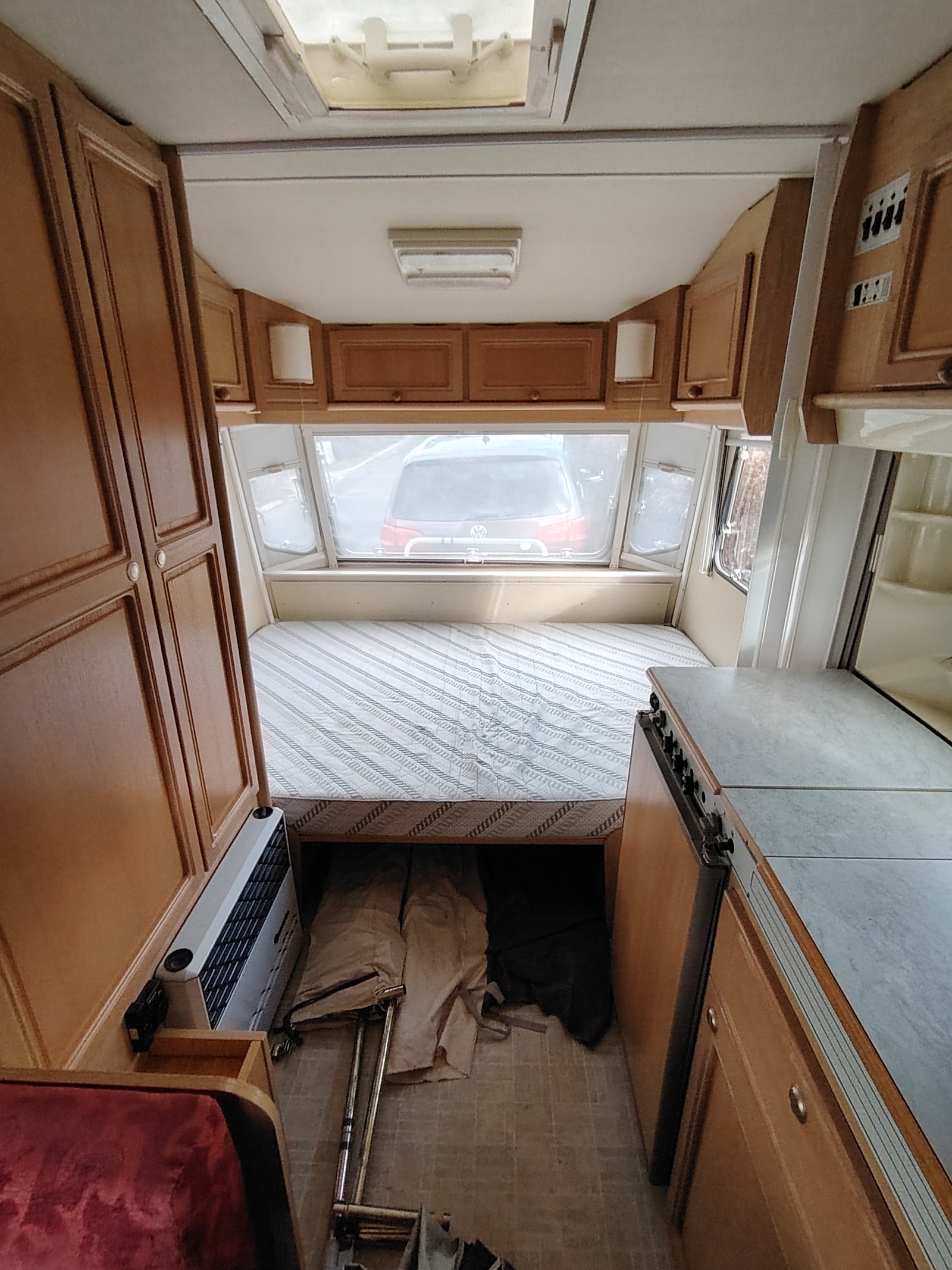 Prostorný interiér karavanu s dvojlůžkem a kuchyňským koutem. Ideální pro pohodlné cestování.