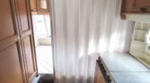 Interiér karavanu s ložnicí a kuchyní, vybavený skříněmi a vytápěním. Komfortní prostor na cestování.