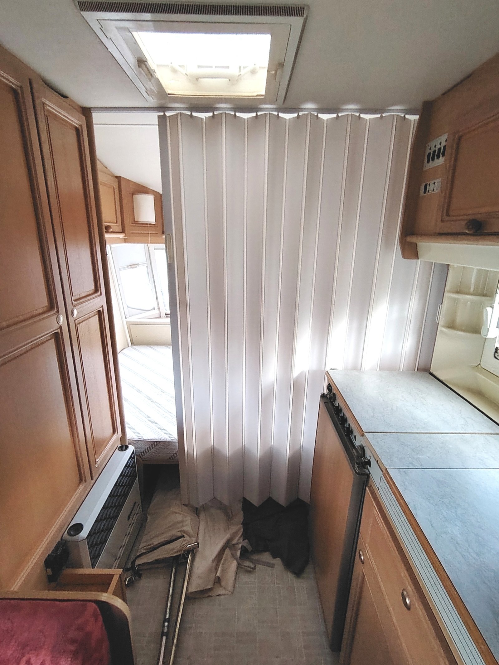 Interiér karavanu s ložnicí a kuchyní, vybavený skříněmi a vytápěním. Komfortní prostor na cestování.