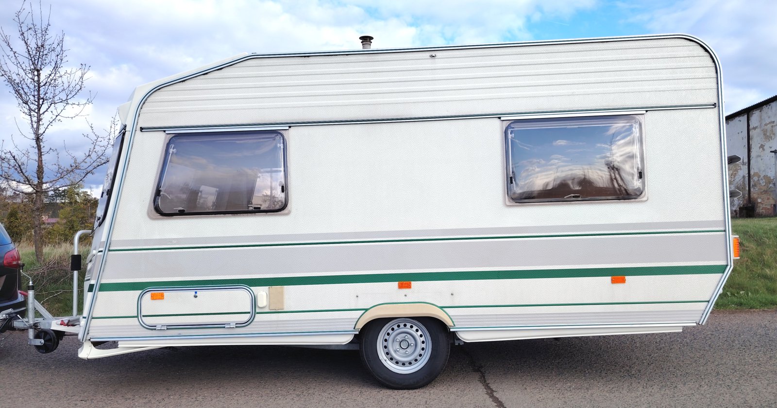 Karavan s bílou karosérií a zelenými pruhy, vhodný pro mobilní cestování a kempování.