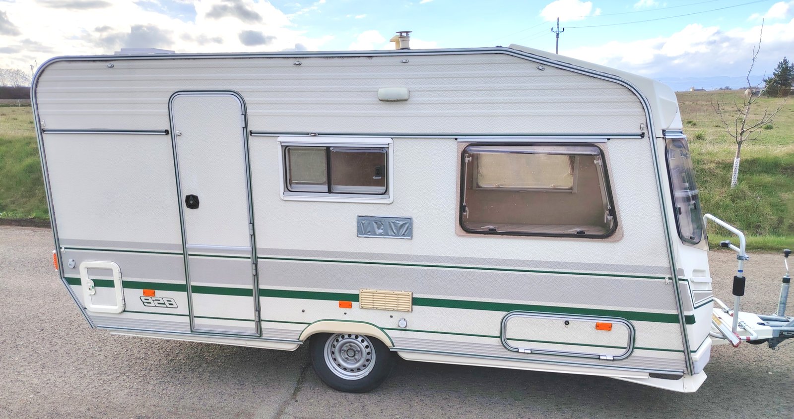 Karavan 928 v elegantním bílém designu s zelenými prvky, ideální pro dobrodružství na cestách.