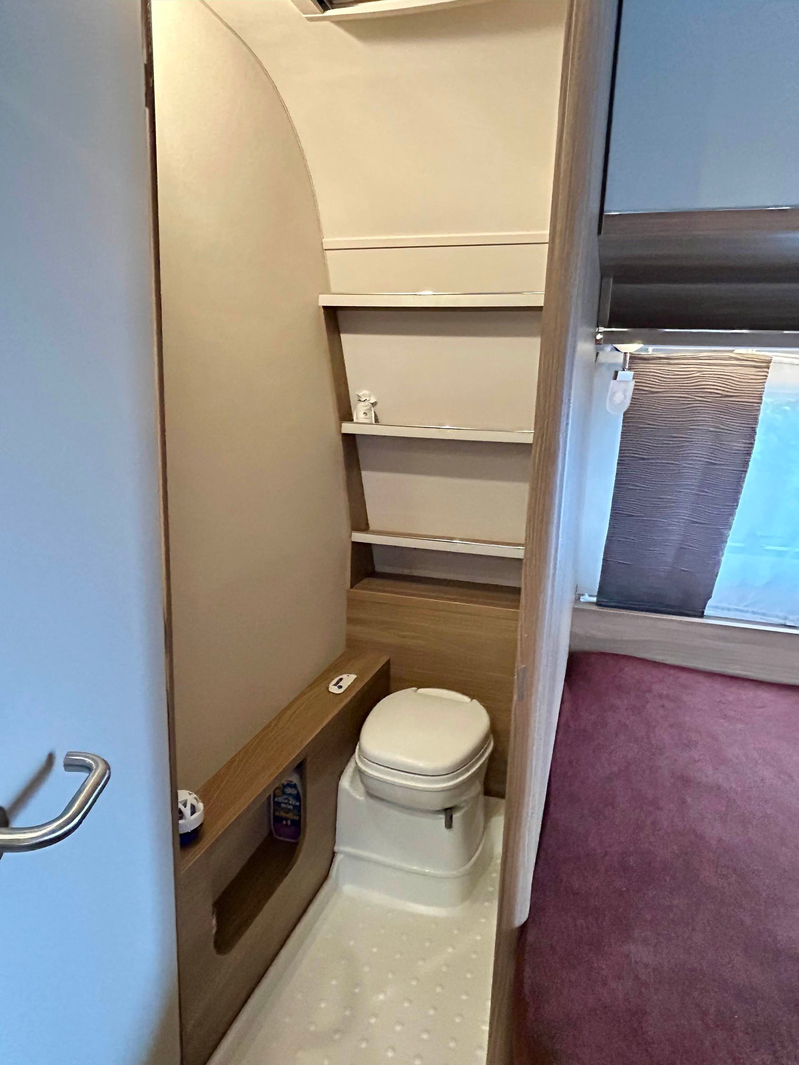 Obrázek interiéru obytného vozu s toaletou a úložnými prostory, ideální pro pohodlné cestování.