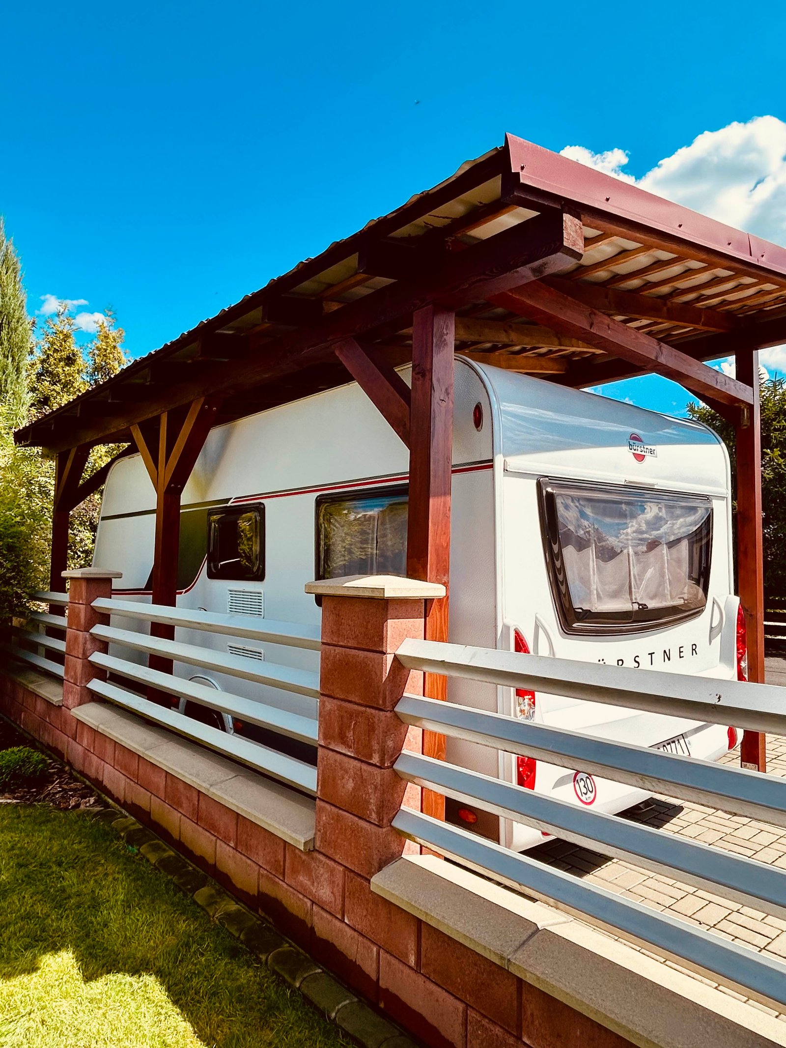 Přívěs za auto Knaus, umístěný pod pergolou, ideální pro letní dobrodružství.