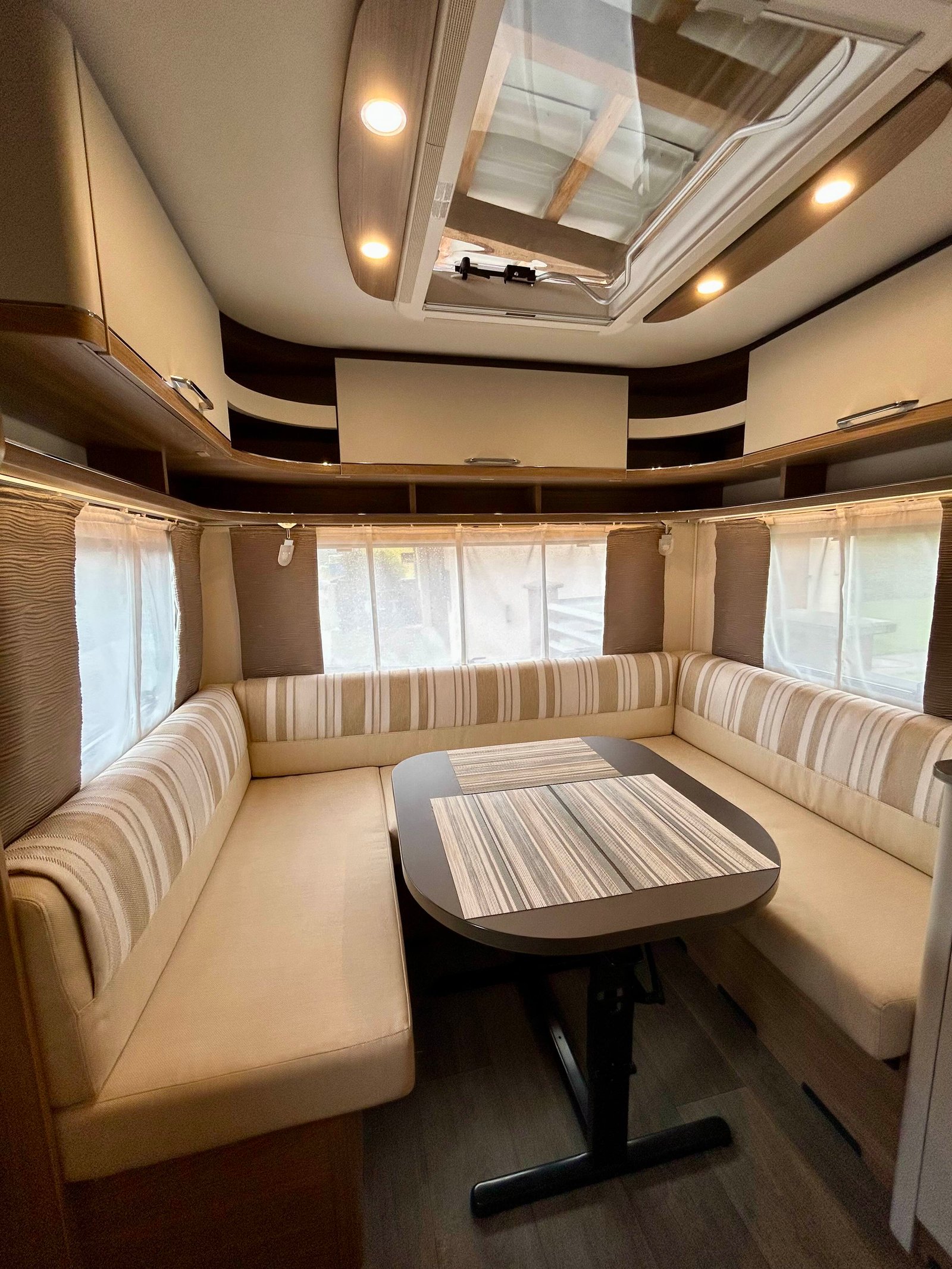 Interiér moderního karavanu s pohodlným sezením a velkým stůl. Světlé a vzdušné prostředí.