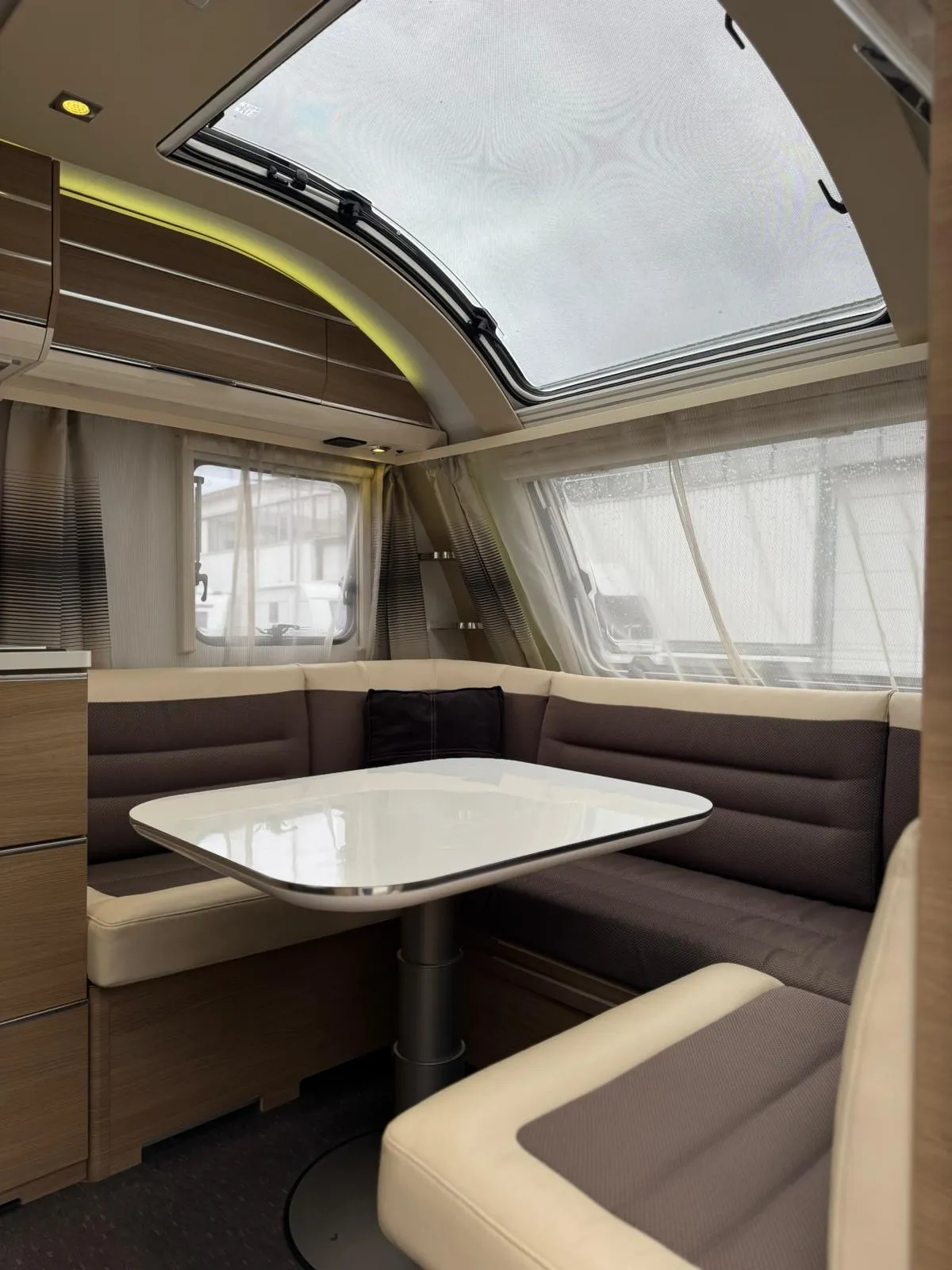 Interiér moderního karavanu s prostorným posezením a velkým oknem pro panoramatický výhled.